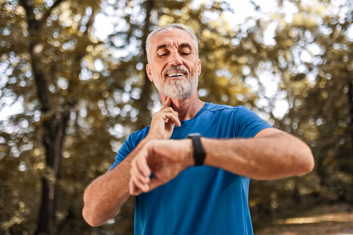 Exercising man in blue t-shirt checking his heart rate.