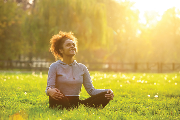 Woman sitting in grass meditating
