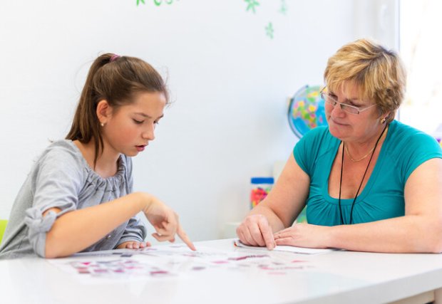 Educator working with a teenage girl with learning difficulties to master logical tests.