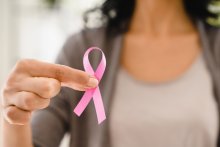 Woman holding pink ribbon for breast cancer awareness
