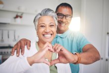 A man and woman making a heart symbol with their hands