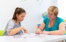 Educador trabajando con una adolescente con dificultades de aprendizaje para dominar pruebas lógicas.